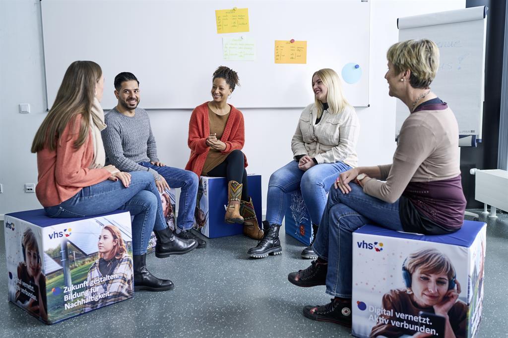 Eine Gruppe von fünf Personen sitzt zusammen im Klassenraum.